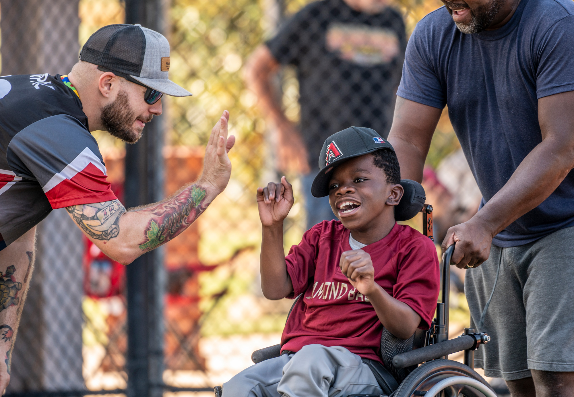 A young baseball player using a wheelchair receives encouragement from coaches