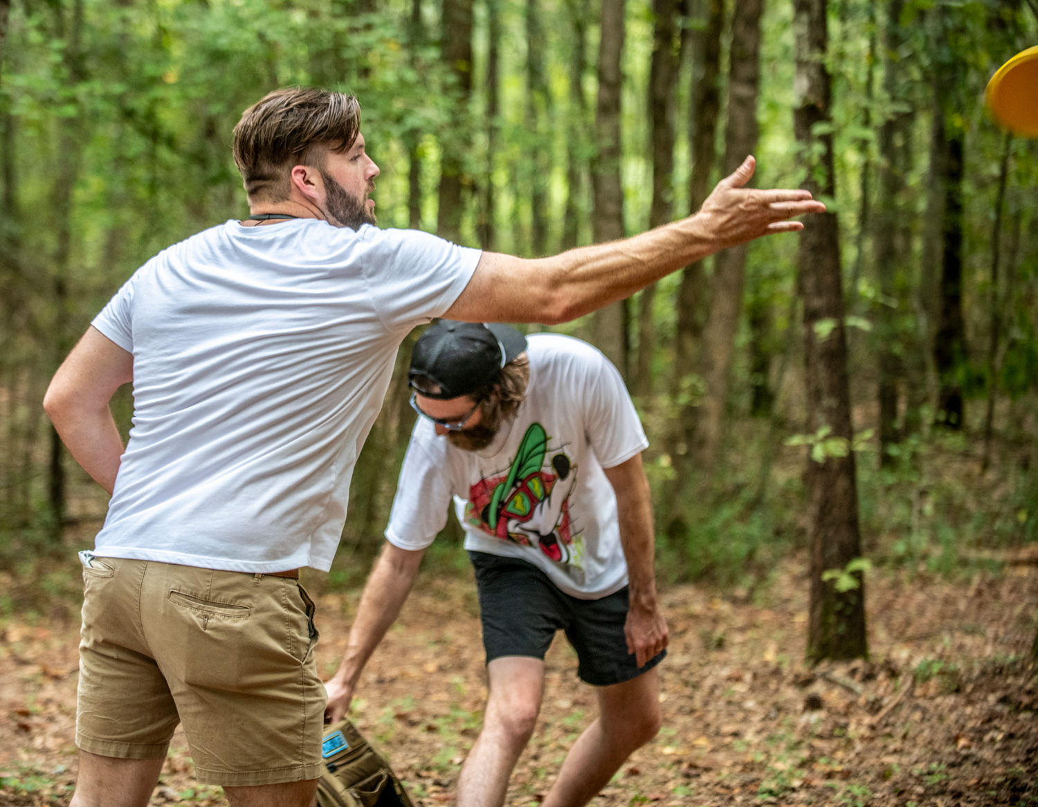 Visitors playing disc golf on a wooded course
